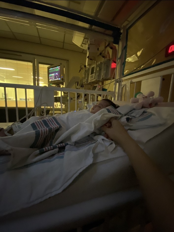 Nancy’s daughter resting in a hospital bed beside care monitors