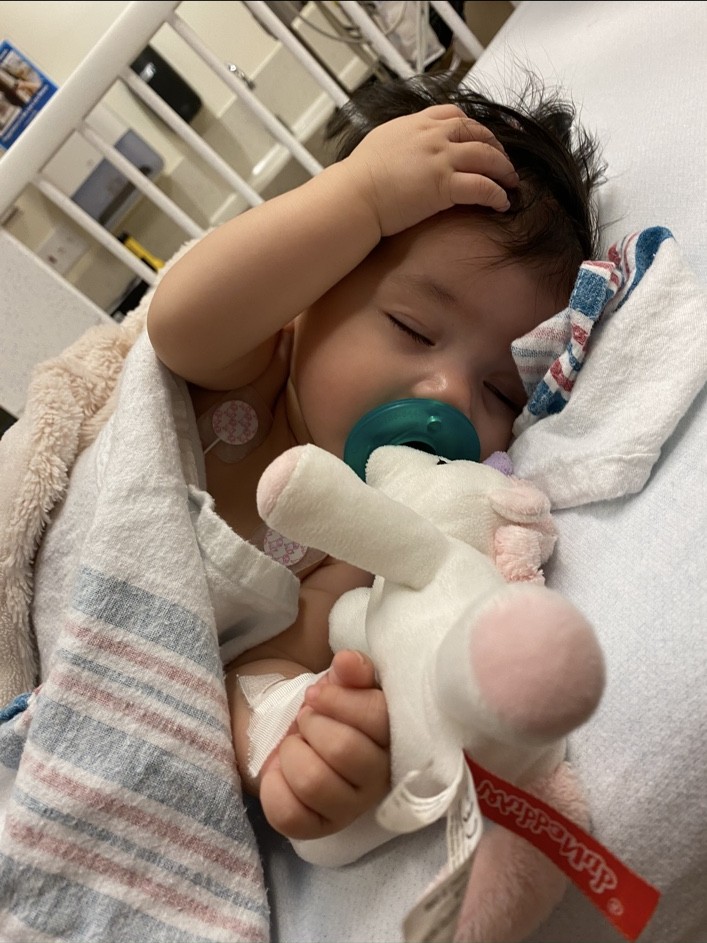 Nancy’s daughter resting in her hospital bed with a stuffed rabbit