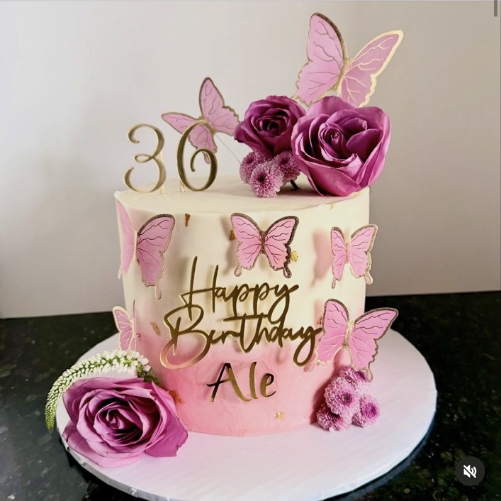 Pink butterfly birthday cake finished with fresh flowers and gold details