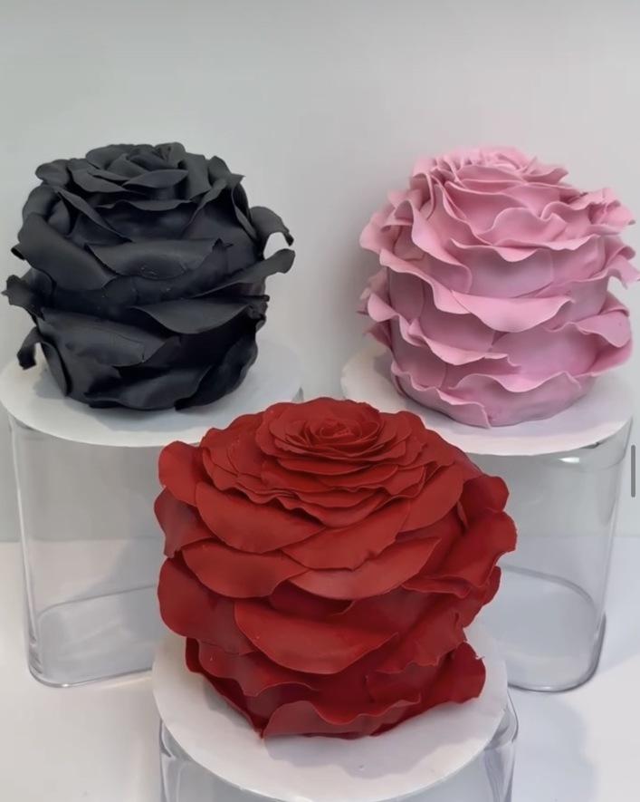 Sculpted rose-shaped cakes in pink, red, and black